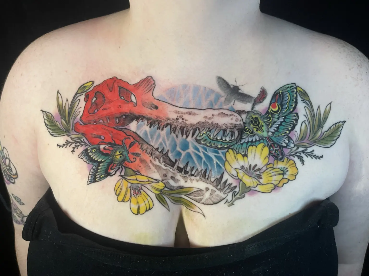 Full-color dinosaur and flower chest tattoo by Keith