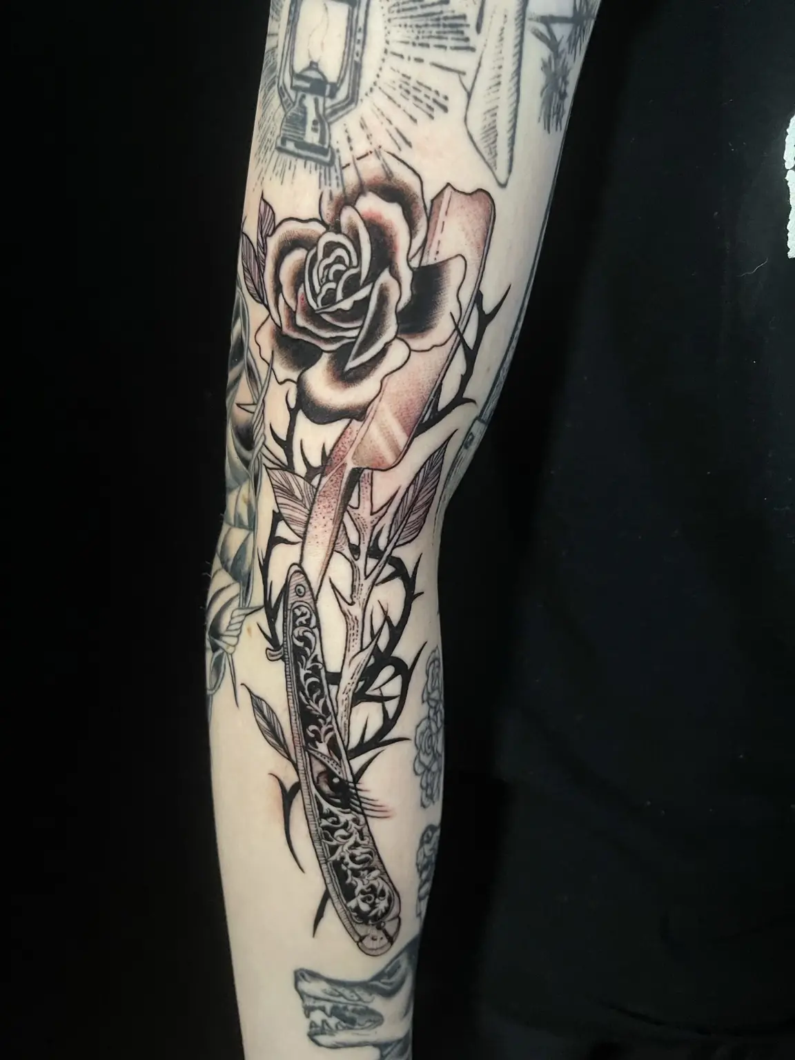 Black-and-gray rose and knife forearm tattoo by Keith