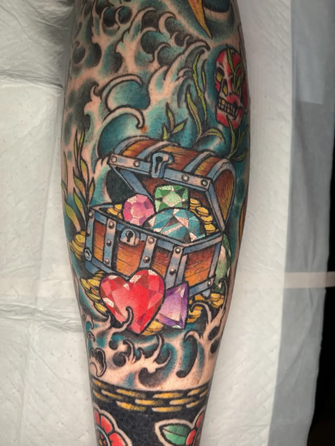 Full-color treasure chest and waves forearm tattoo by Keith